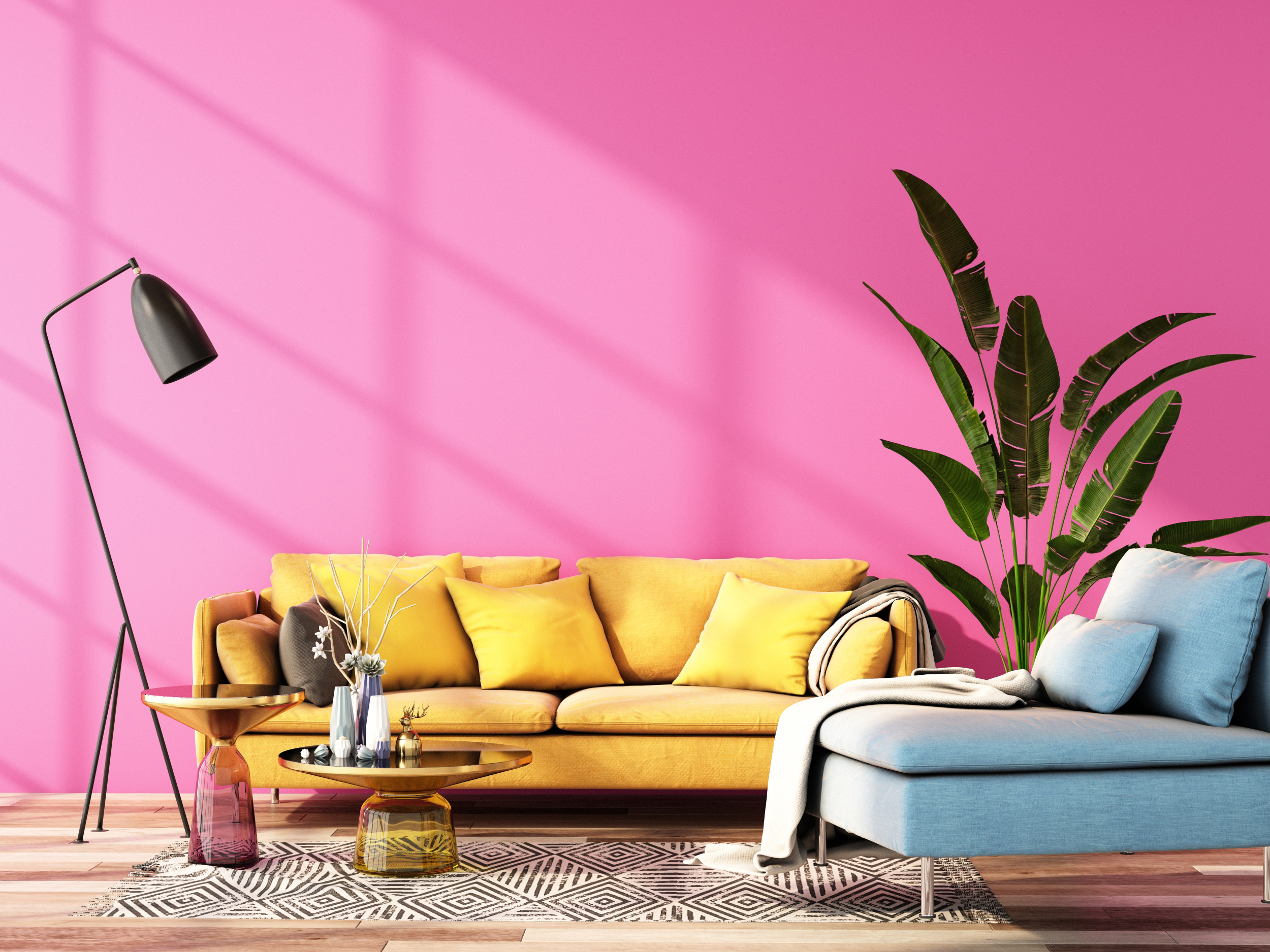 A imagem mostra uma sala com parede rosa chiclete, sofá amarelo de três lugares, uma poltrona azul no lado direito e uma planta entre ambos. Além disso, em frente ao sofa amarelo, duas mesas de apoio , um tapete e luminária ao canto.